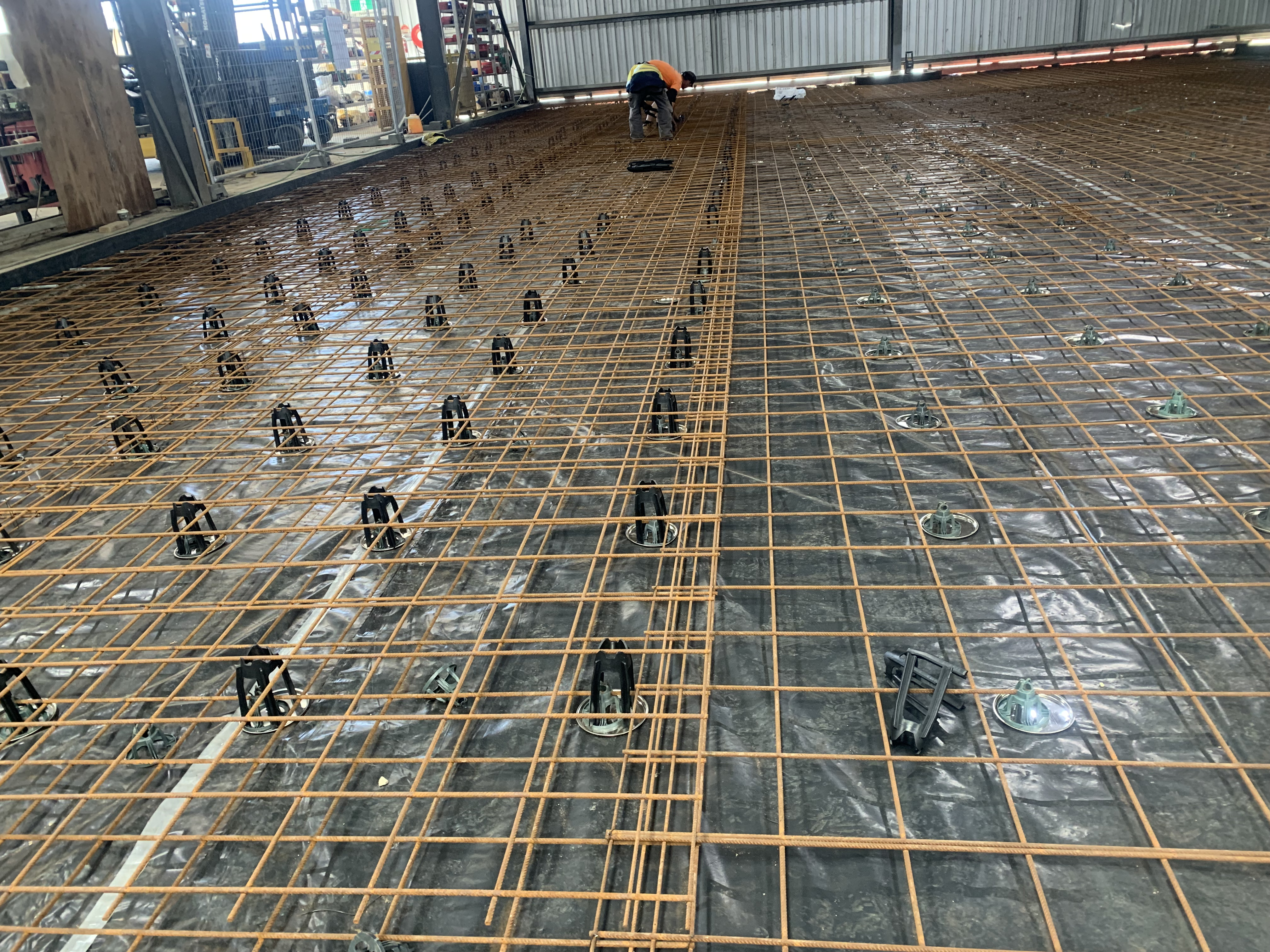 Indoor warehouse concrete floor slab preparation — reo mesh laid over plastic membrane