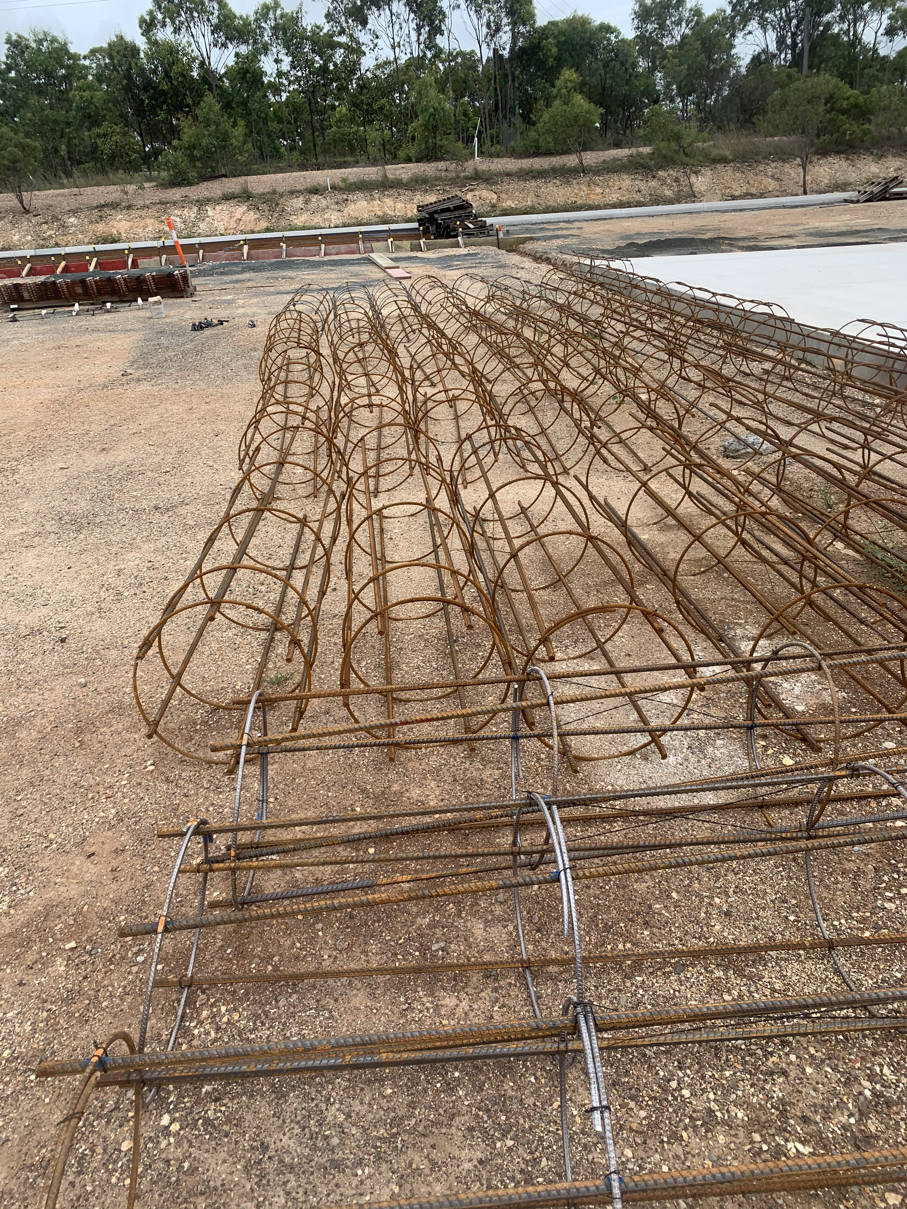 Long rows of circular reo cage stirrups laid out at staging area ready for installation