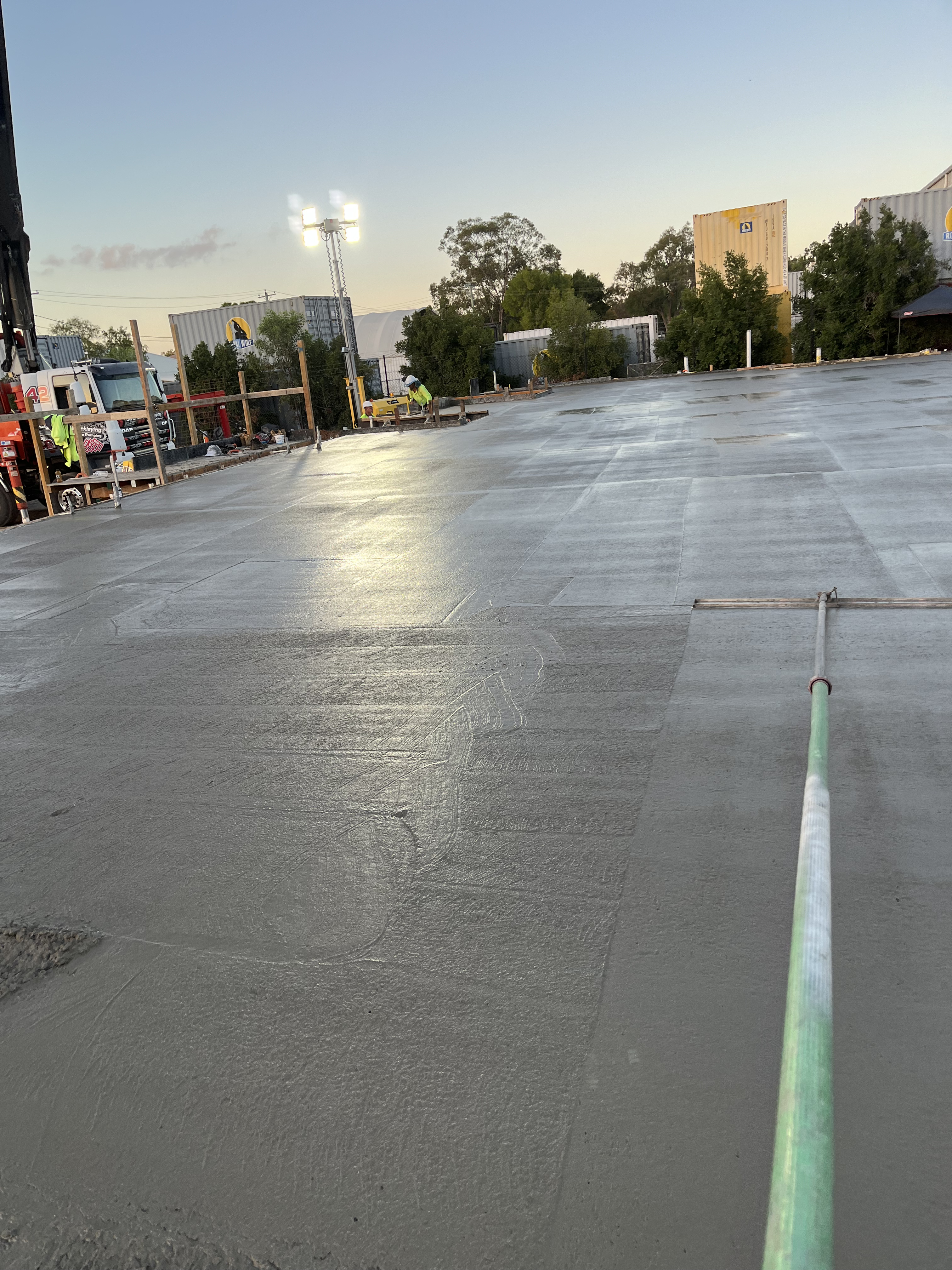Commercial concrete slab pour at night — workers and floodlights on large site