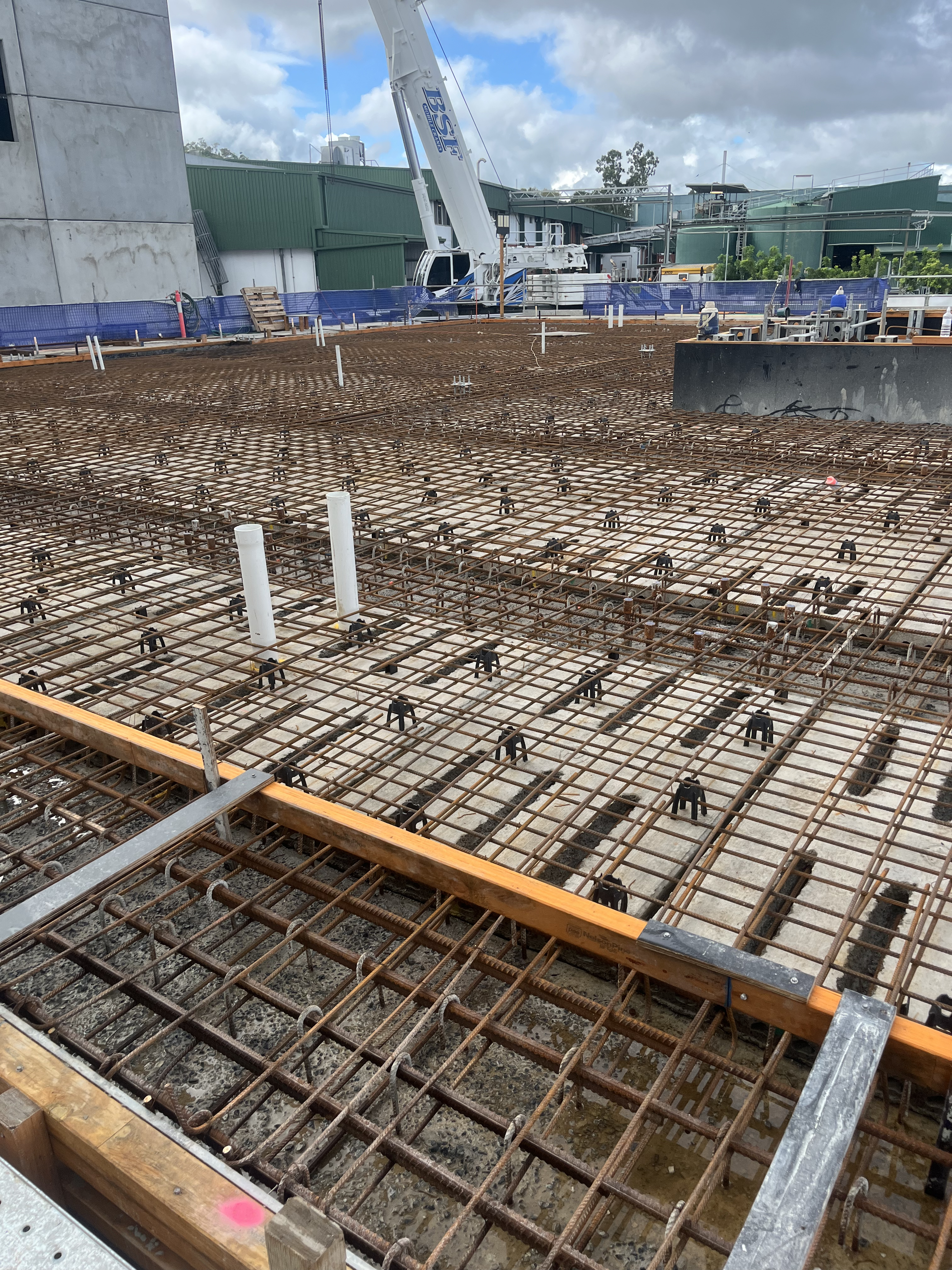 Commercial concrete slab with crane and workers visible — large scale project