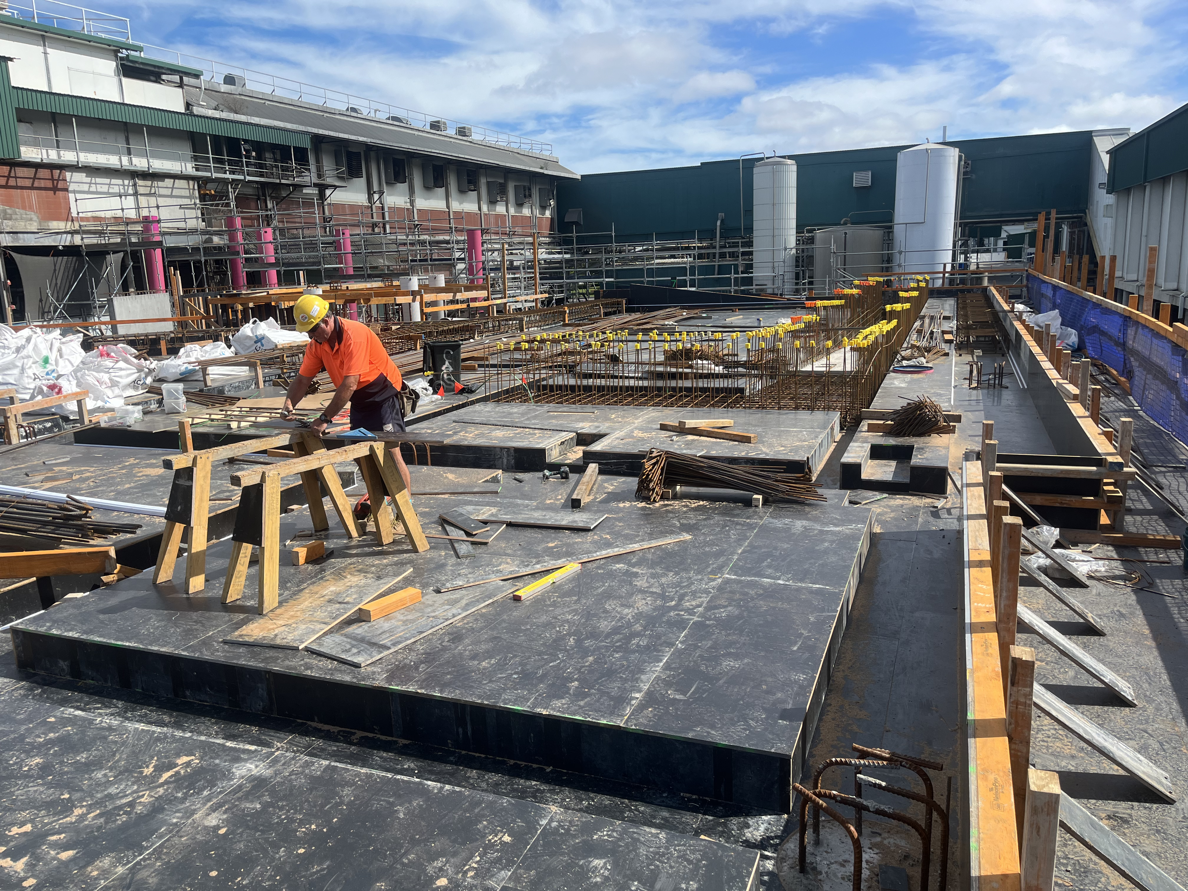 Worker in hi-vis cutting formwork on a large commercial concrete slab